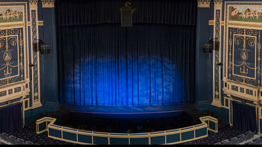 Image of the interior of the Baldwin Theatre showing  the stage with dramatic blue stage lights.