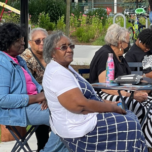 People seated at tables int the park relaxing